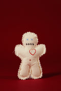 White voodoo doll with red heart and black markings on a red background