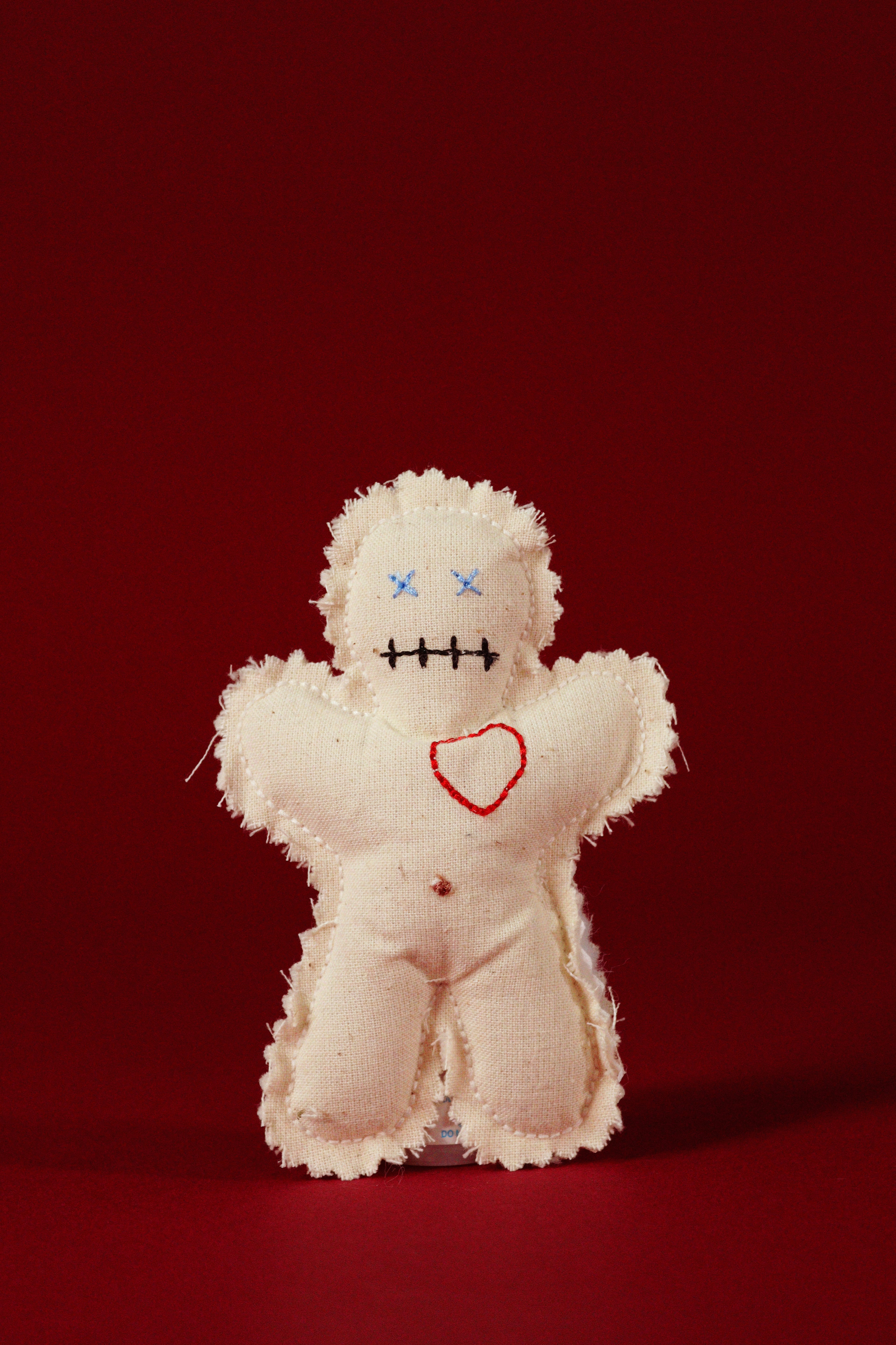 White voodoo doll with red heart and black markings on a red background