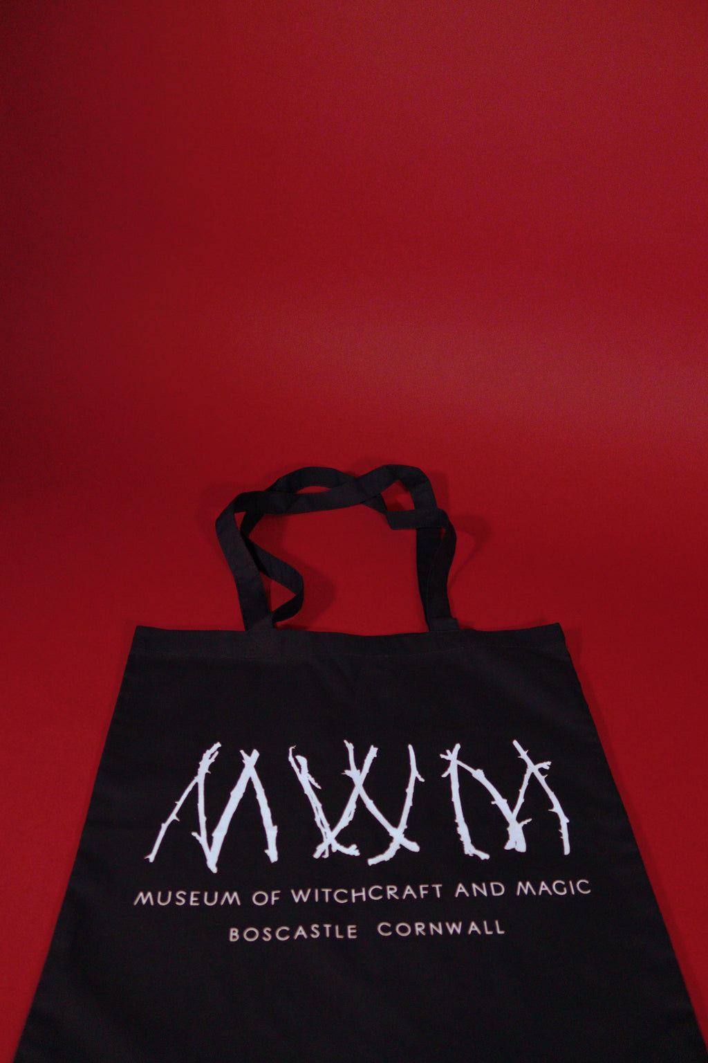 Black tote bag with white text and design on a red background