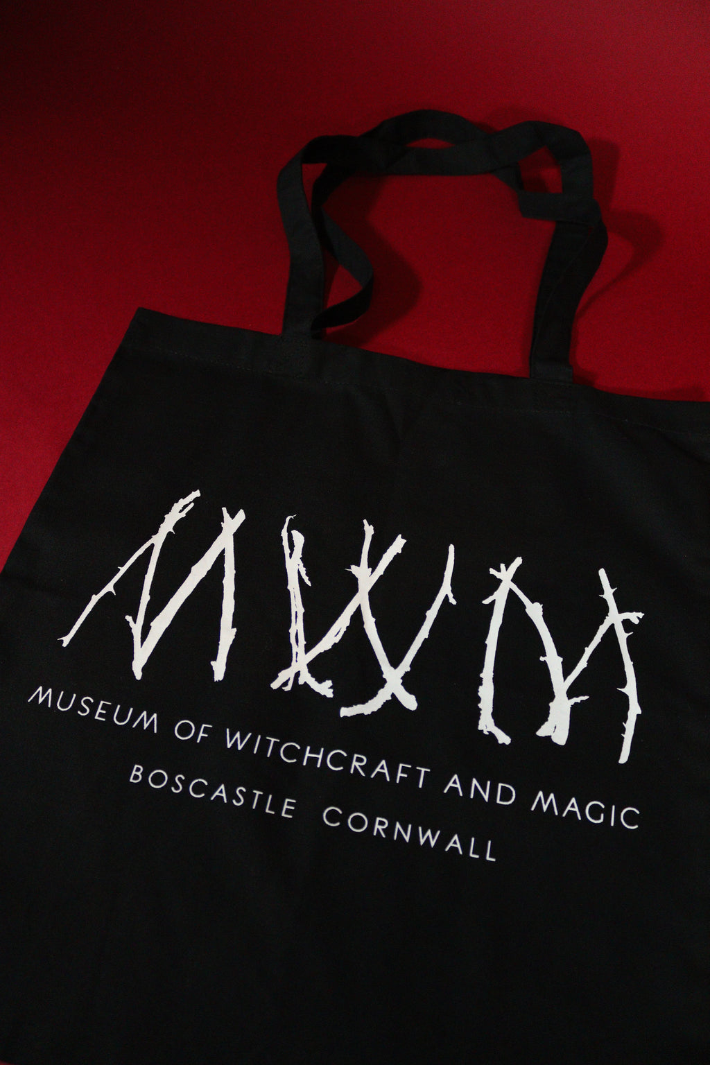 Black tote bag with white text and design on a red background
