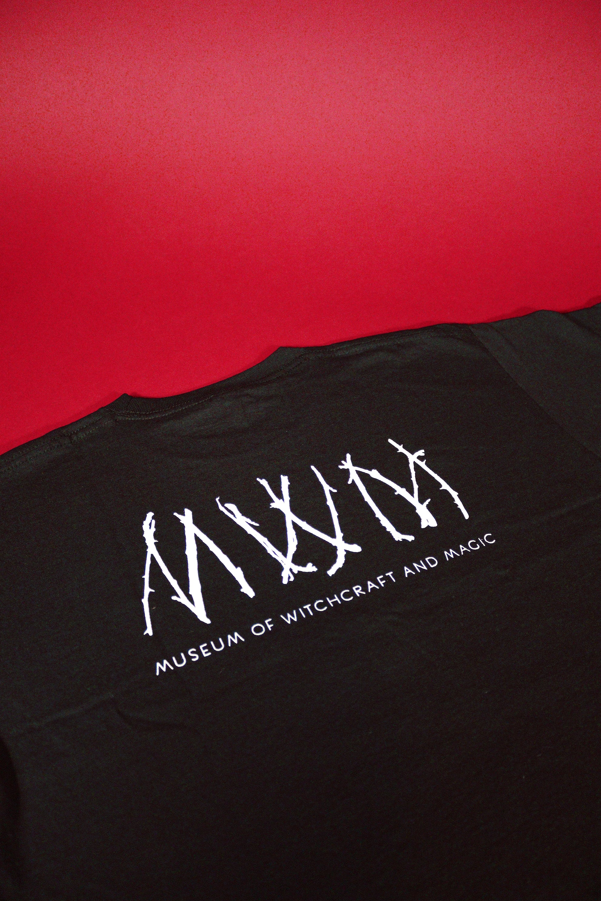 Black t-shirt with white logo and text on a red background