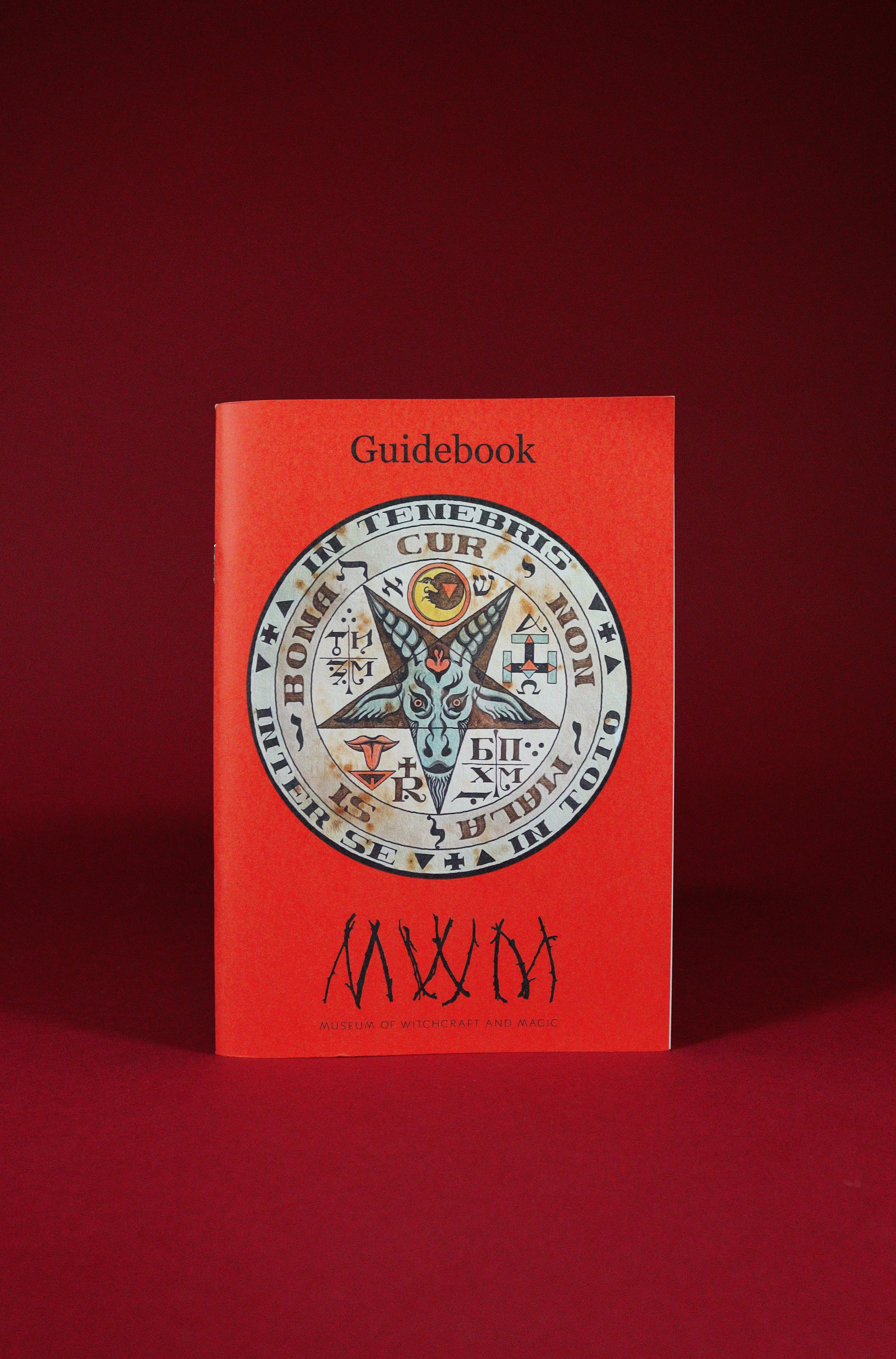 Red guidebook with a central emblem on a red background