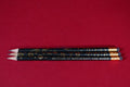 Three pencils with decorative designs and 'Museum of Witchcraft and Magic' text on a red background