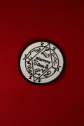 Black and white circular emblem with text on a red background