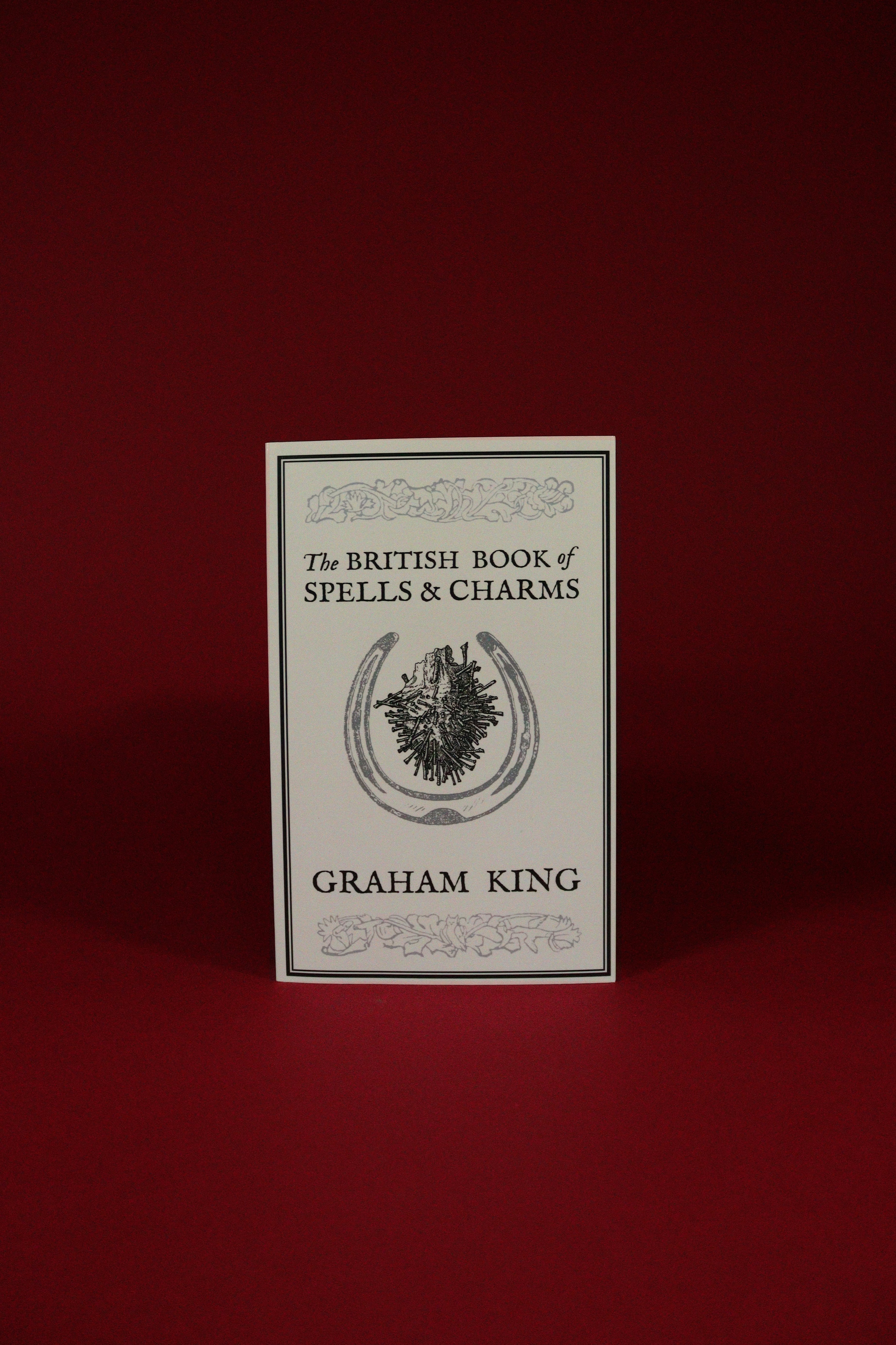 Book titled 'The British Book of Spells & Charms' by Graham King on a red background