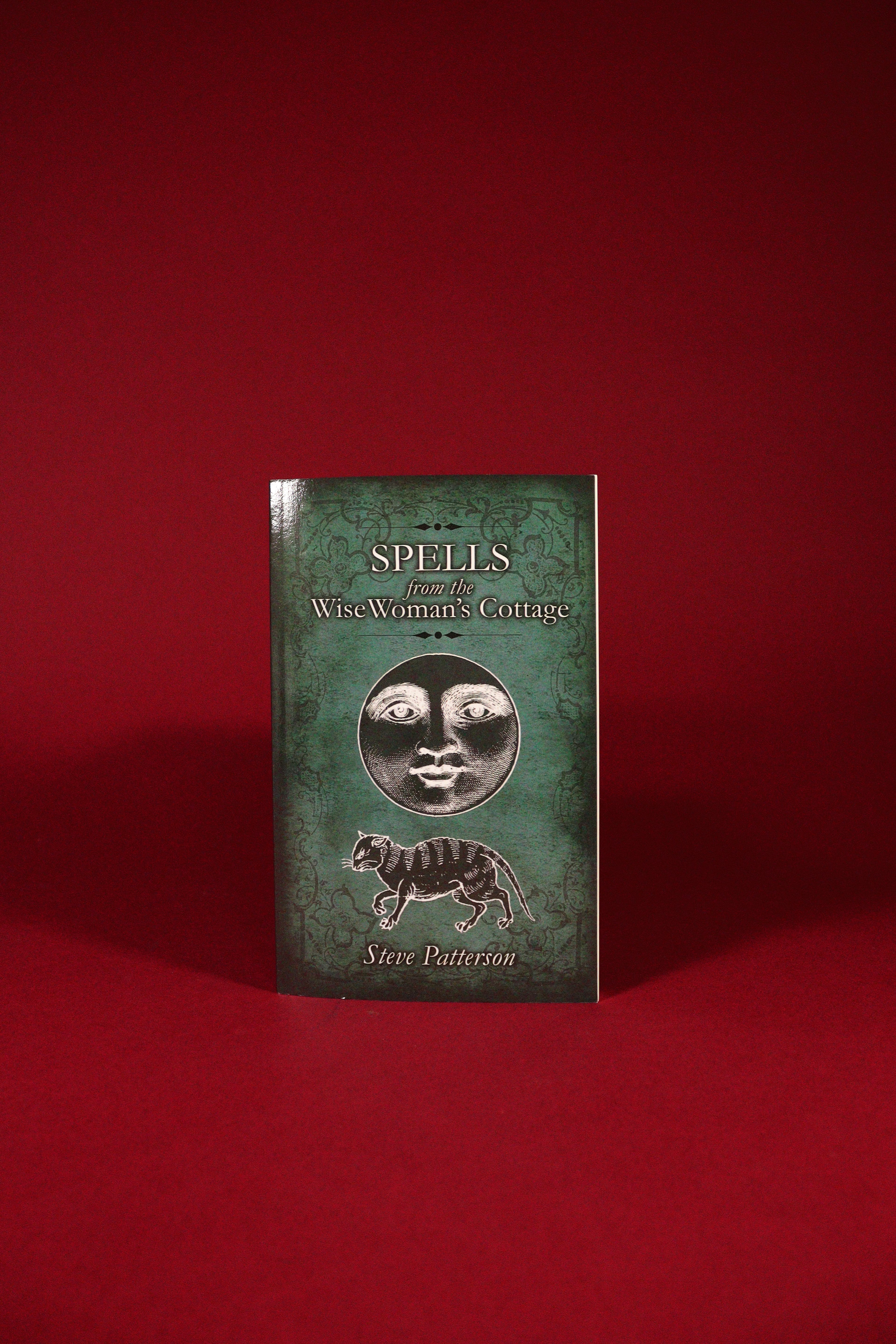 Book titled 'Spells from the Wise Woman's Cottage' on a red background