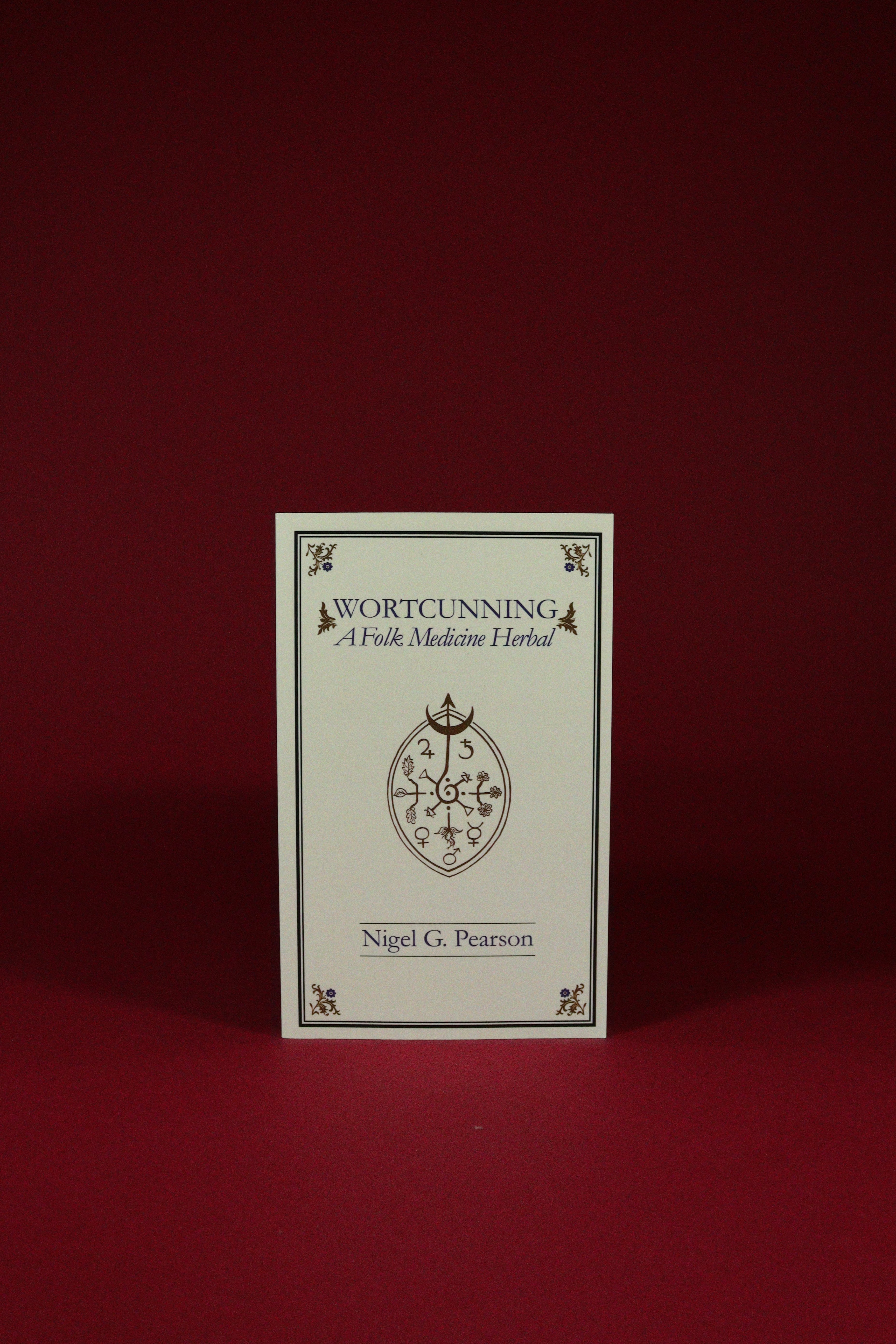Book titled 'Wortcunning: A Folk Medicine Herbal' by Nigel G. Pearson on a red background