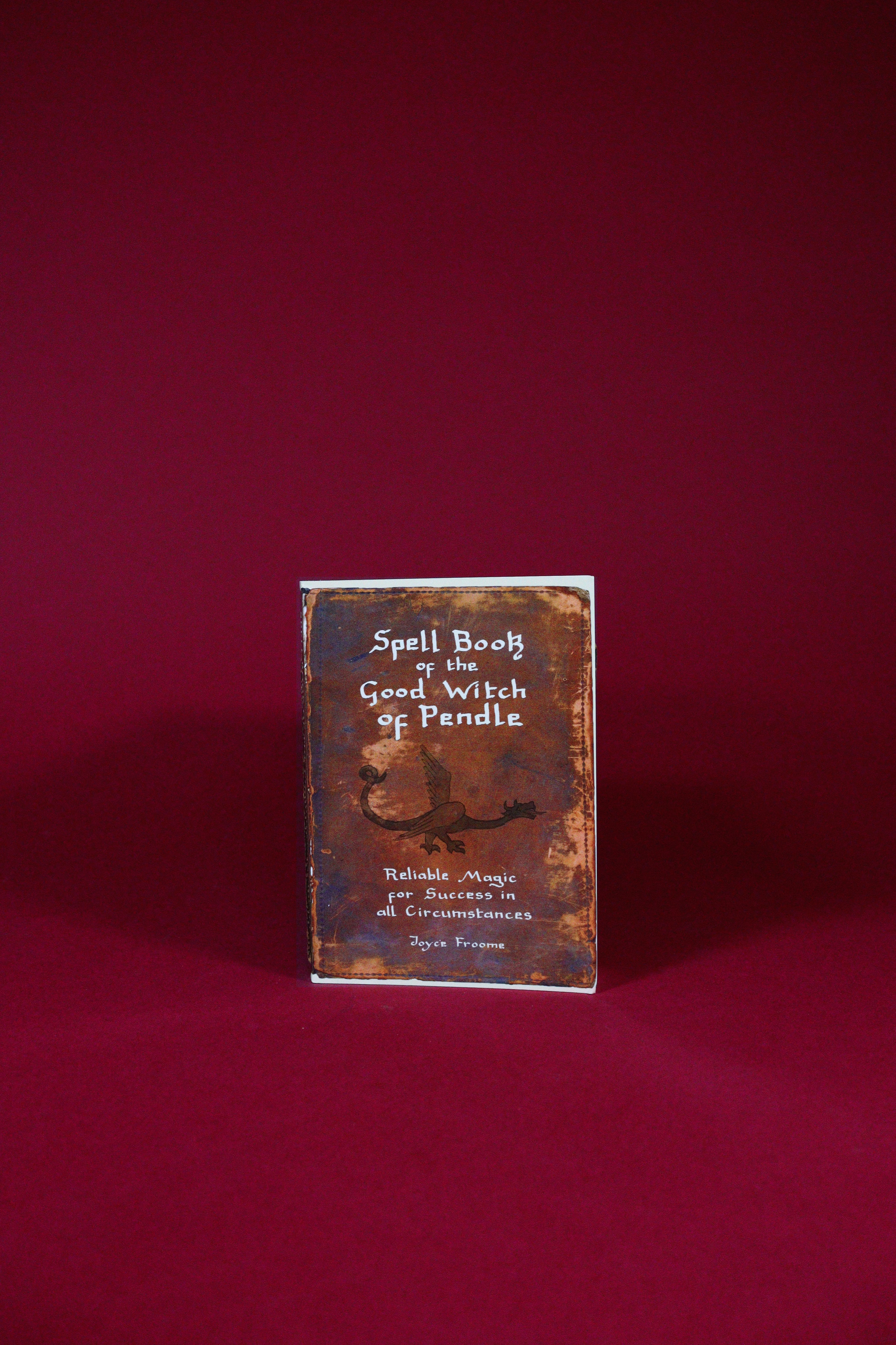 Book titled 'Spell Book of the Good Witch of Pendle' on a red background