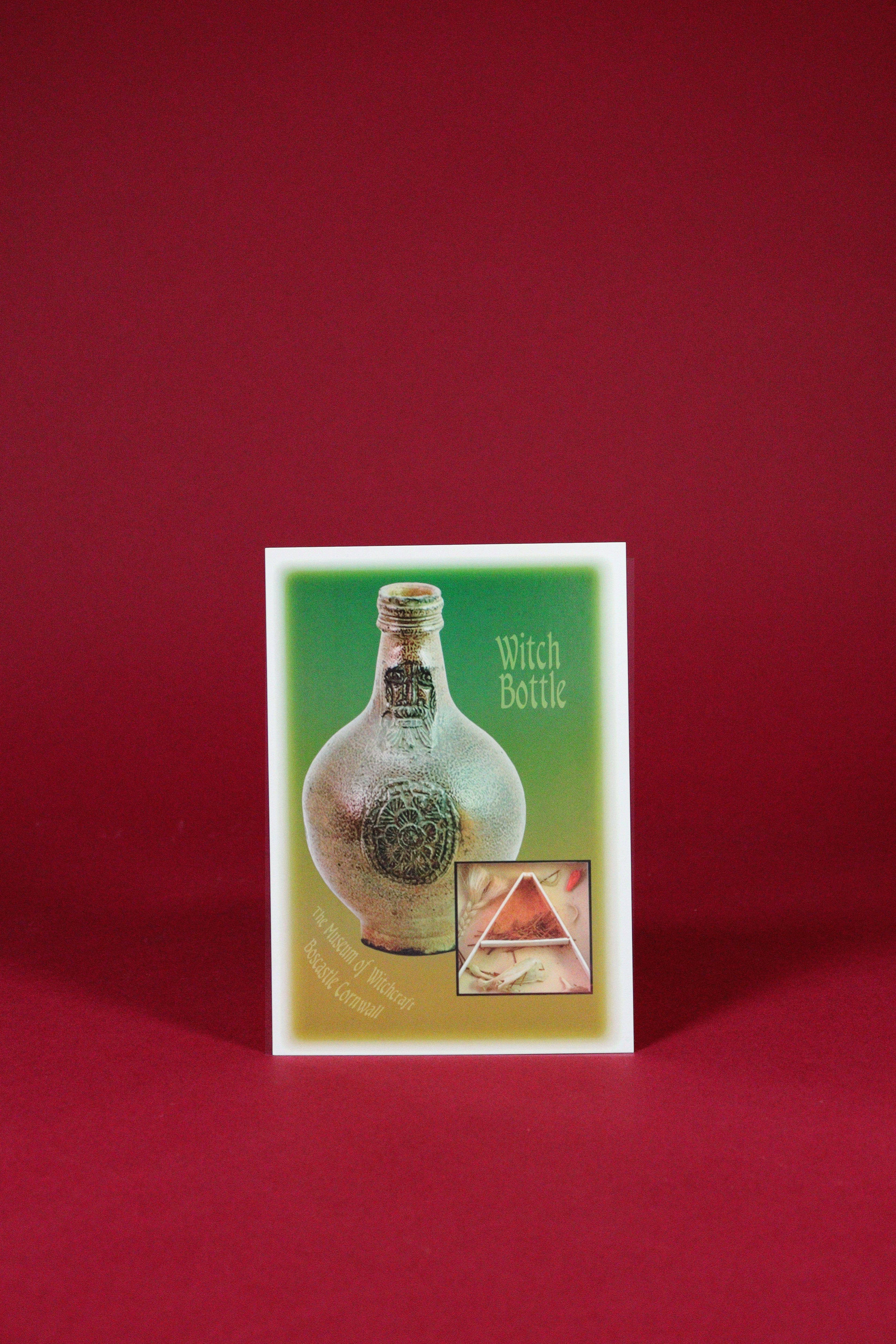 Card with a witch bottle design on a red background