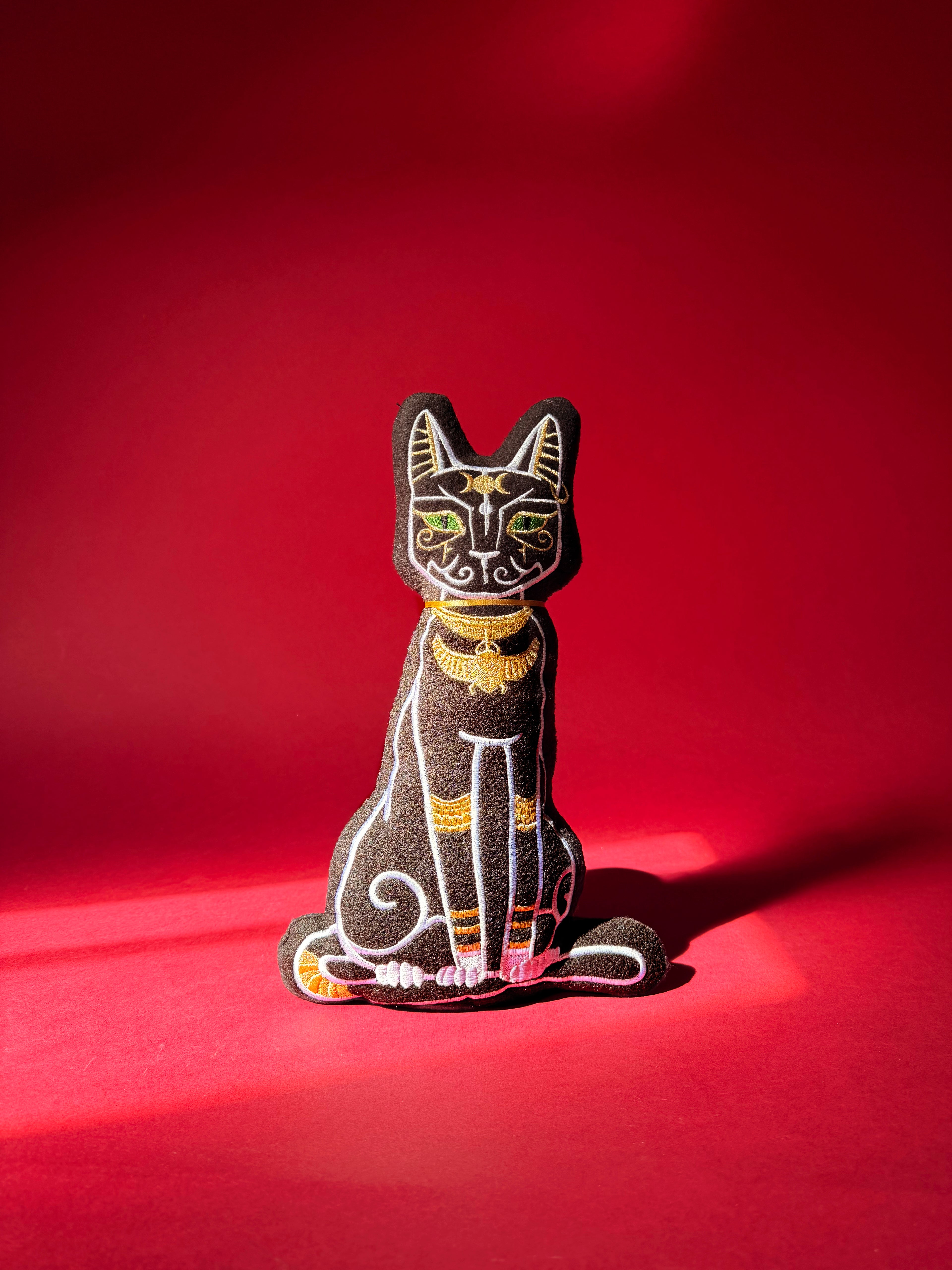 Decorative cat figurine with black and gold details on a red background