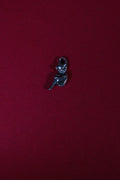 Small silver pisky charm on a red background