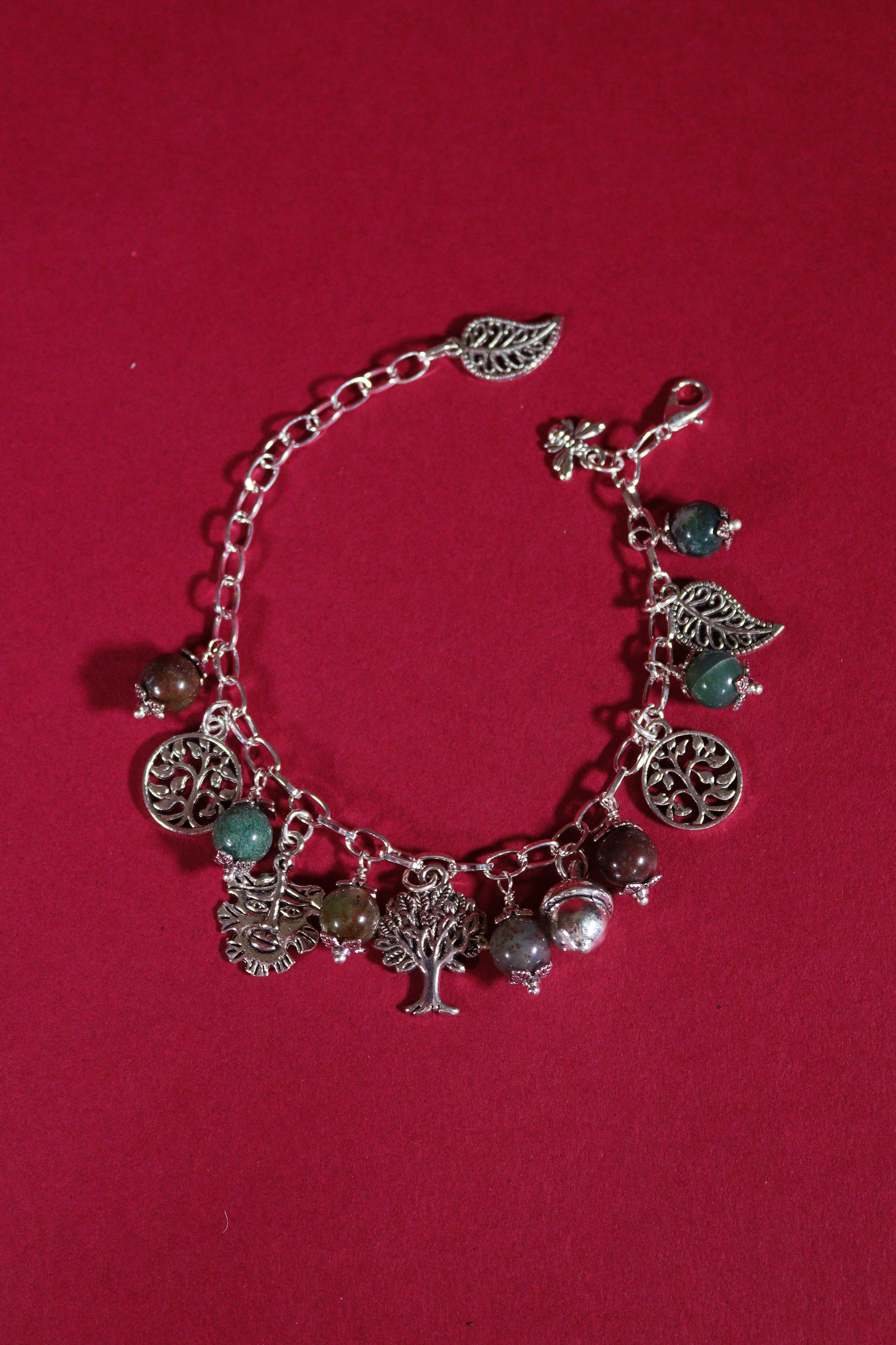 Silver charm bracelet with various charms on a red background