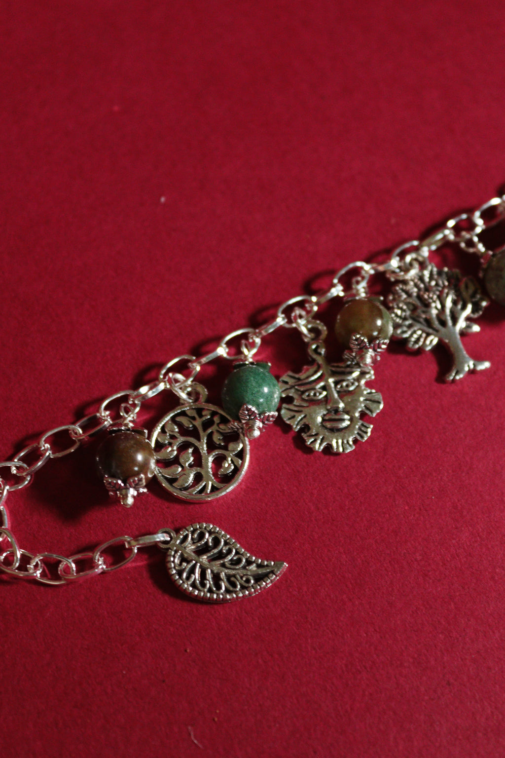 Bracelet with tree of life and leaf charms on a red background