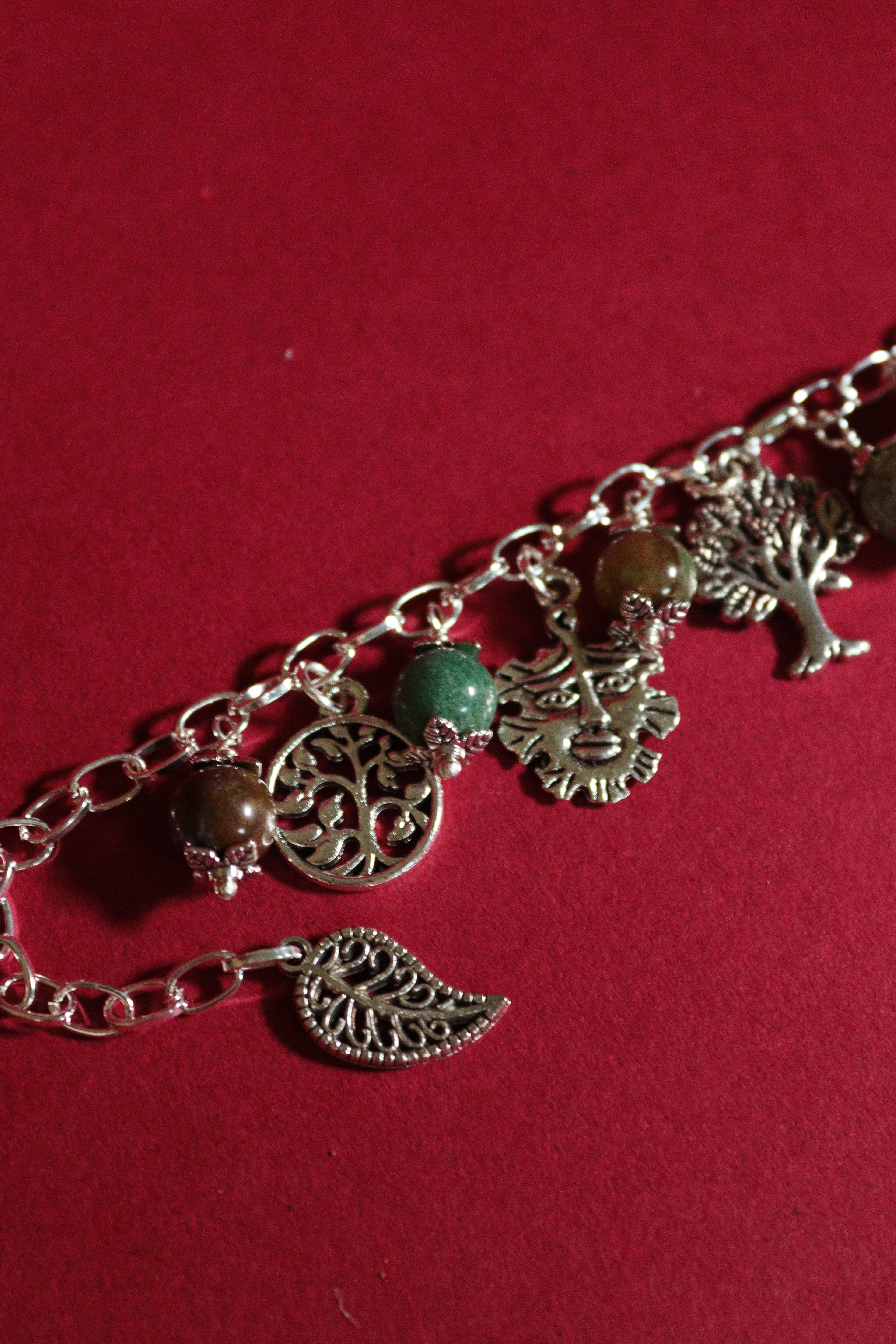 Bracelet with tree of life and leaf charms on a red background