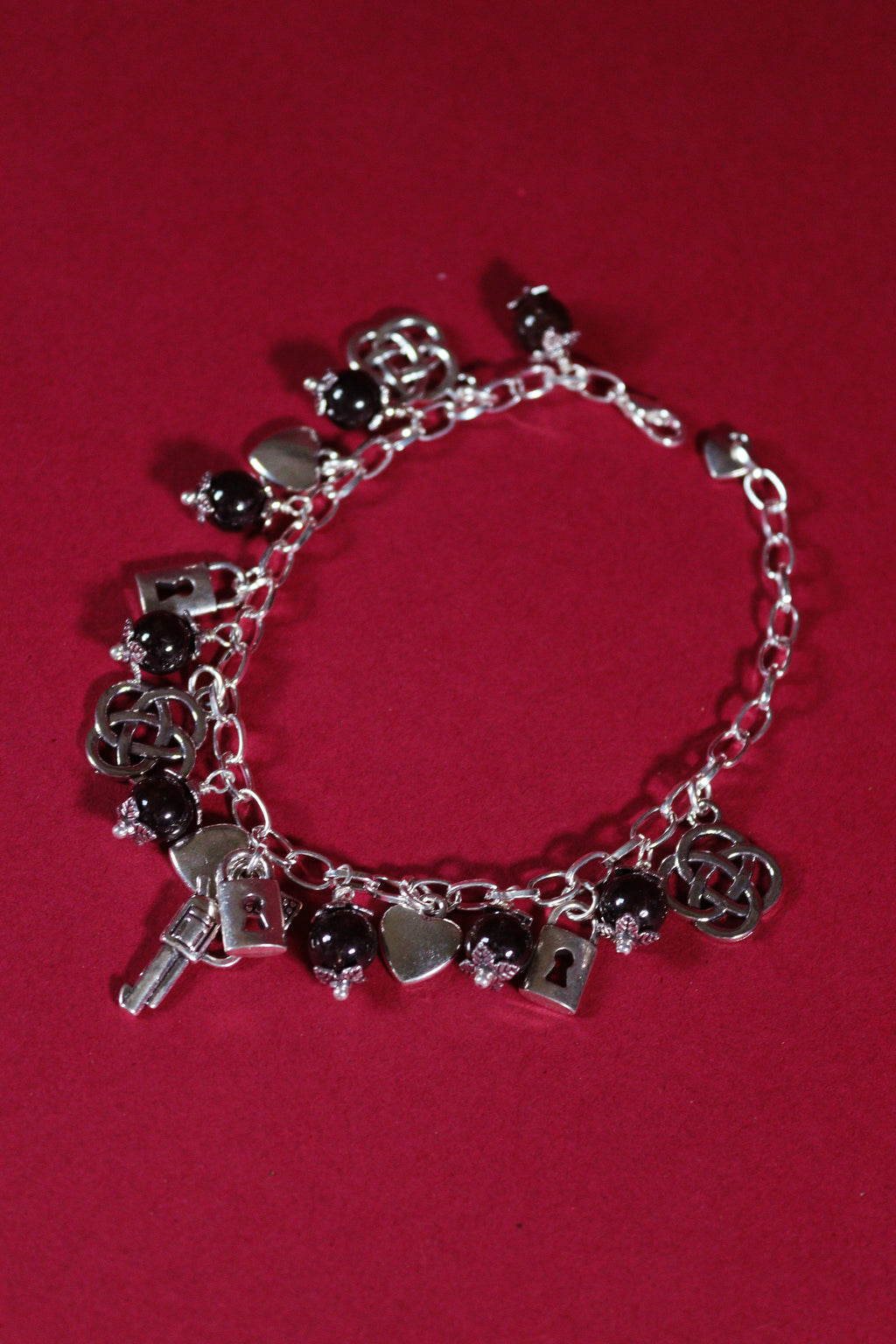 Silver bracelet with charms on a red background