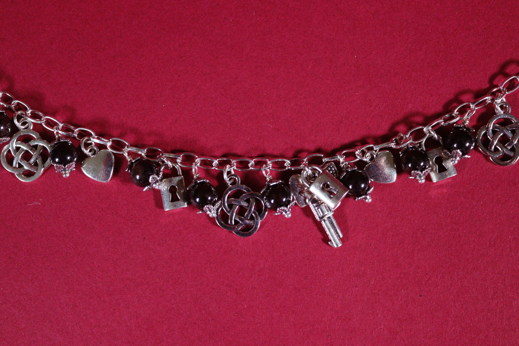 Silver charm bracelet with various charms on a red background