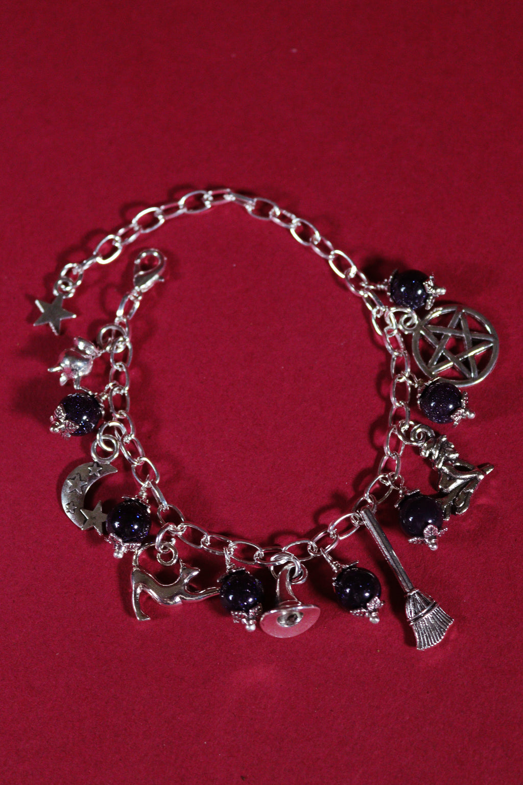 Silver charm bracelet with various charms on a red background
