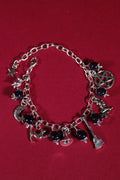 Silver charm bracelet with various charms on a red background