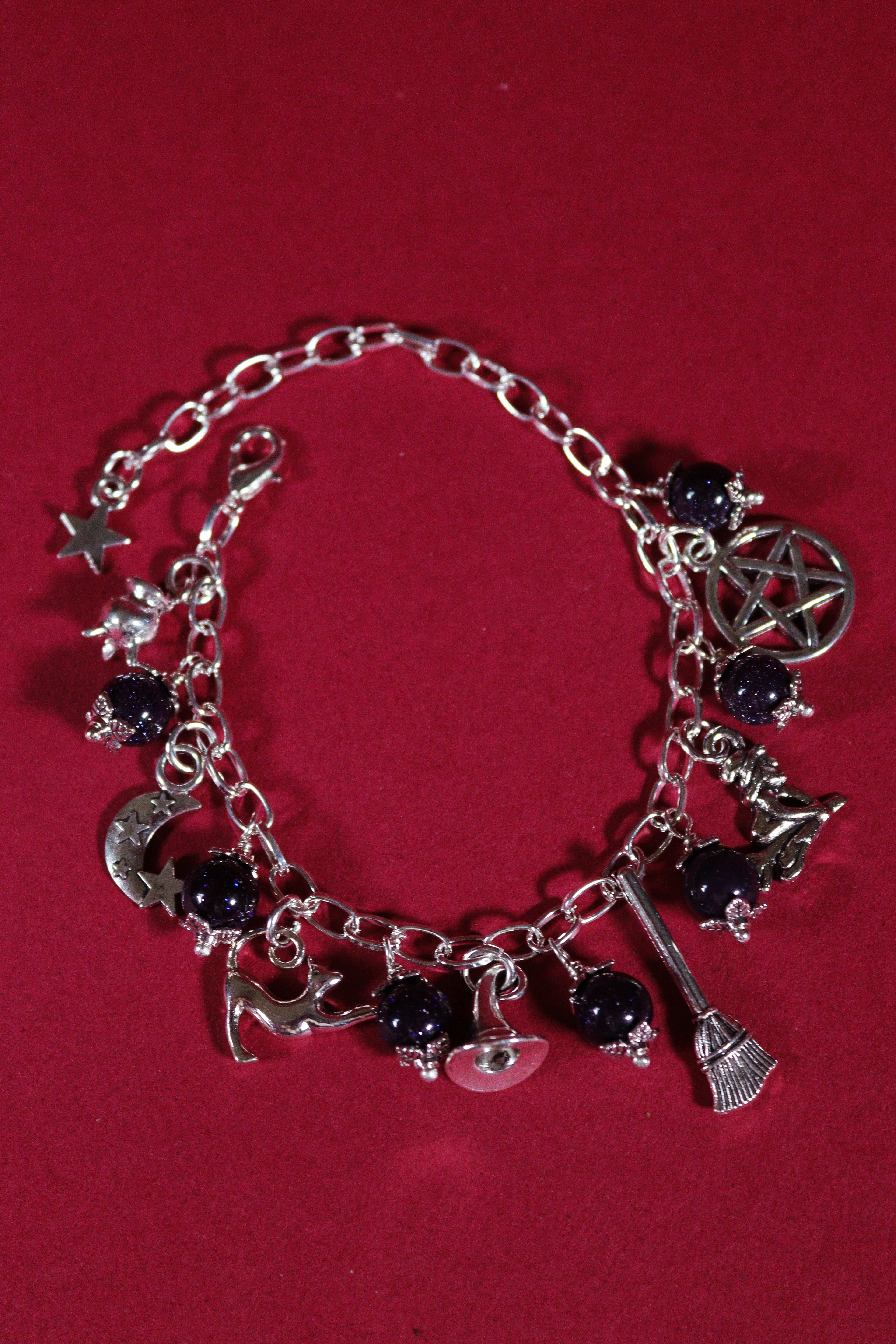 Silver charm bracelet with various charms on a red background