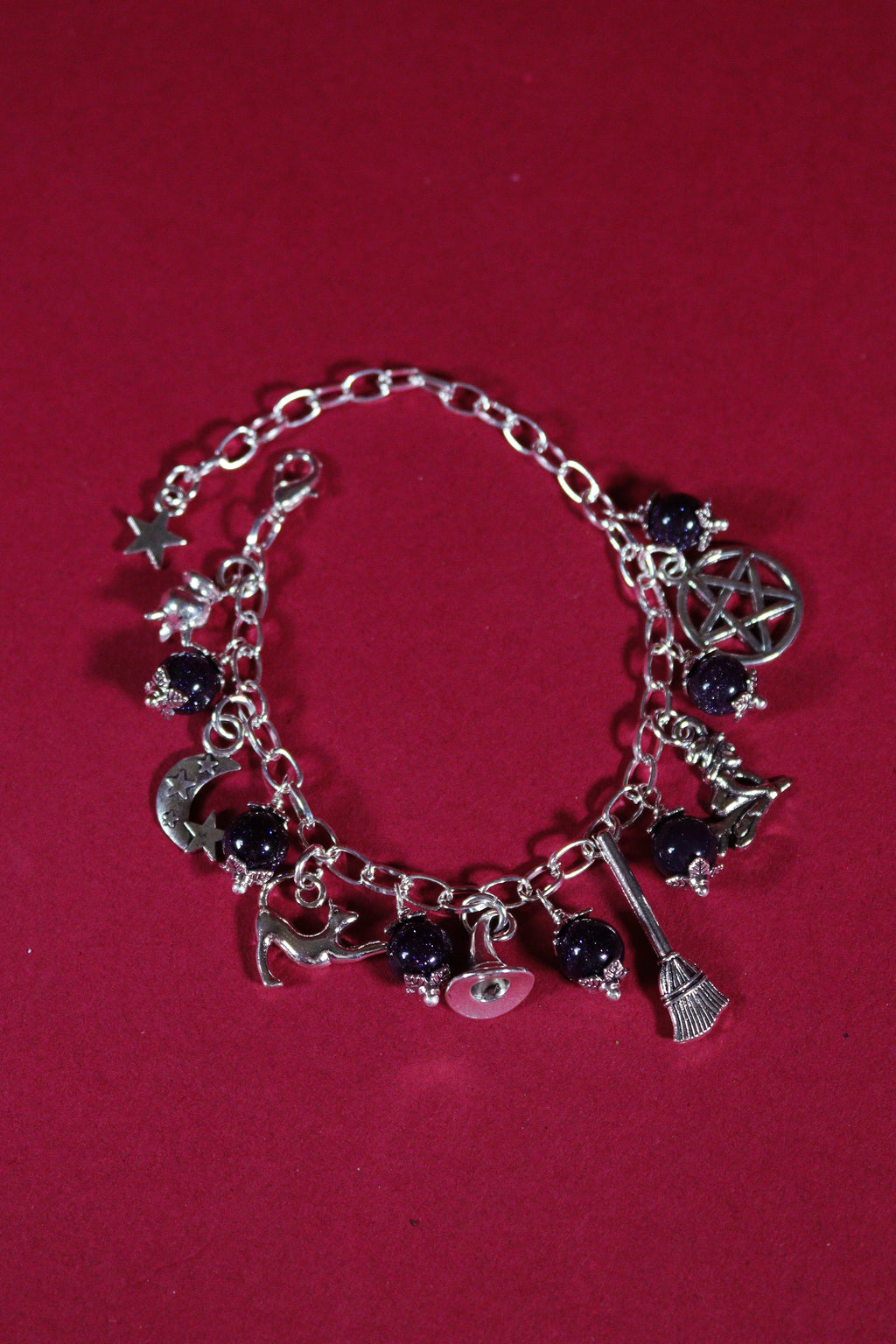 Silver bracelet with various charms on a red background