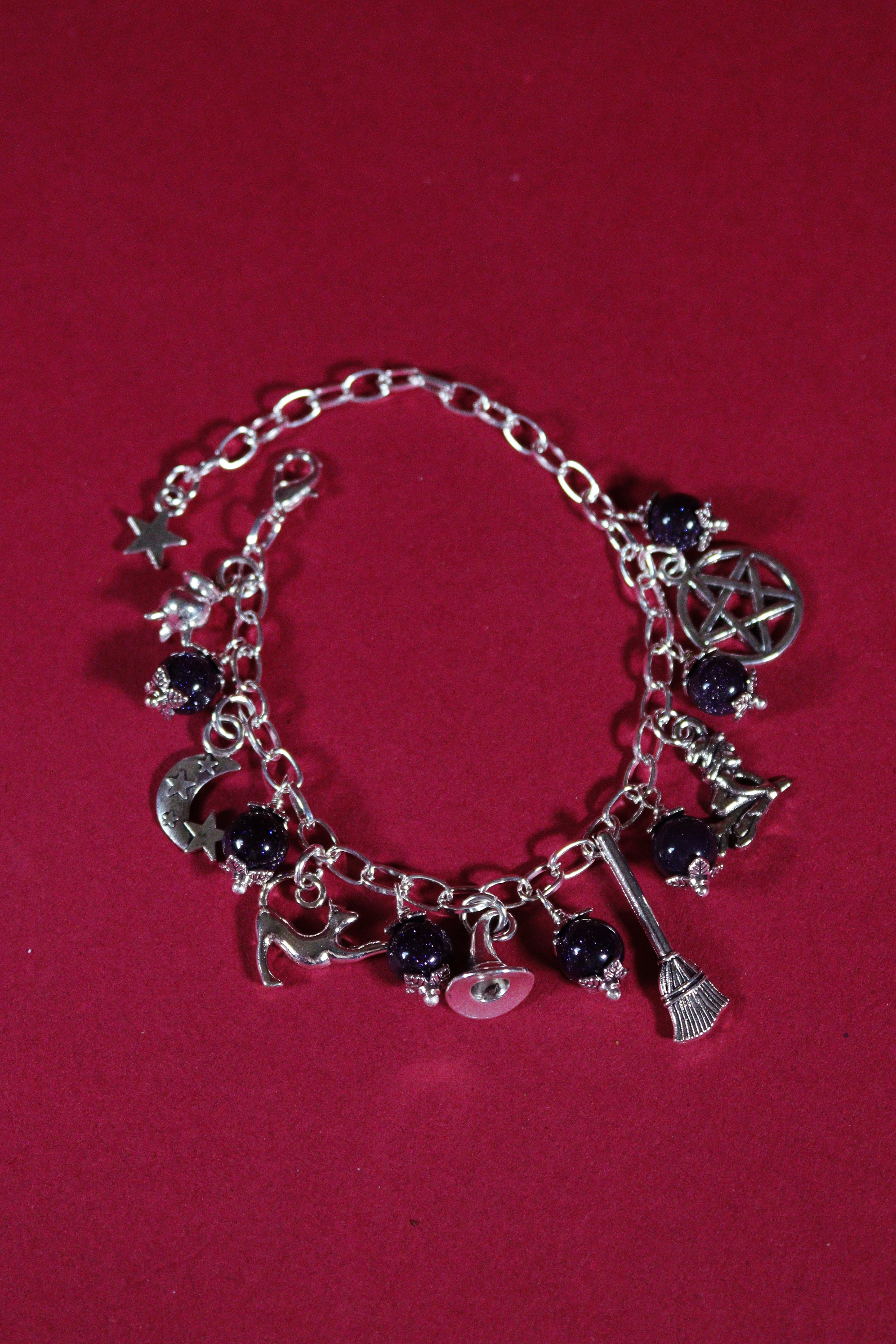 Silver bracelet with various charms on a red background