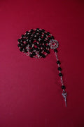 Black beaded rosary with silver cross on a red background
