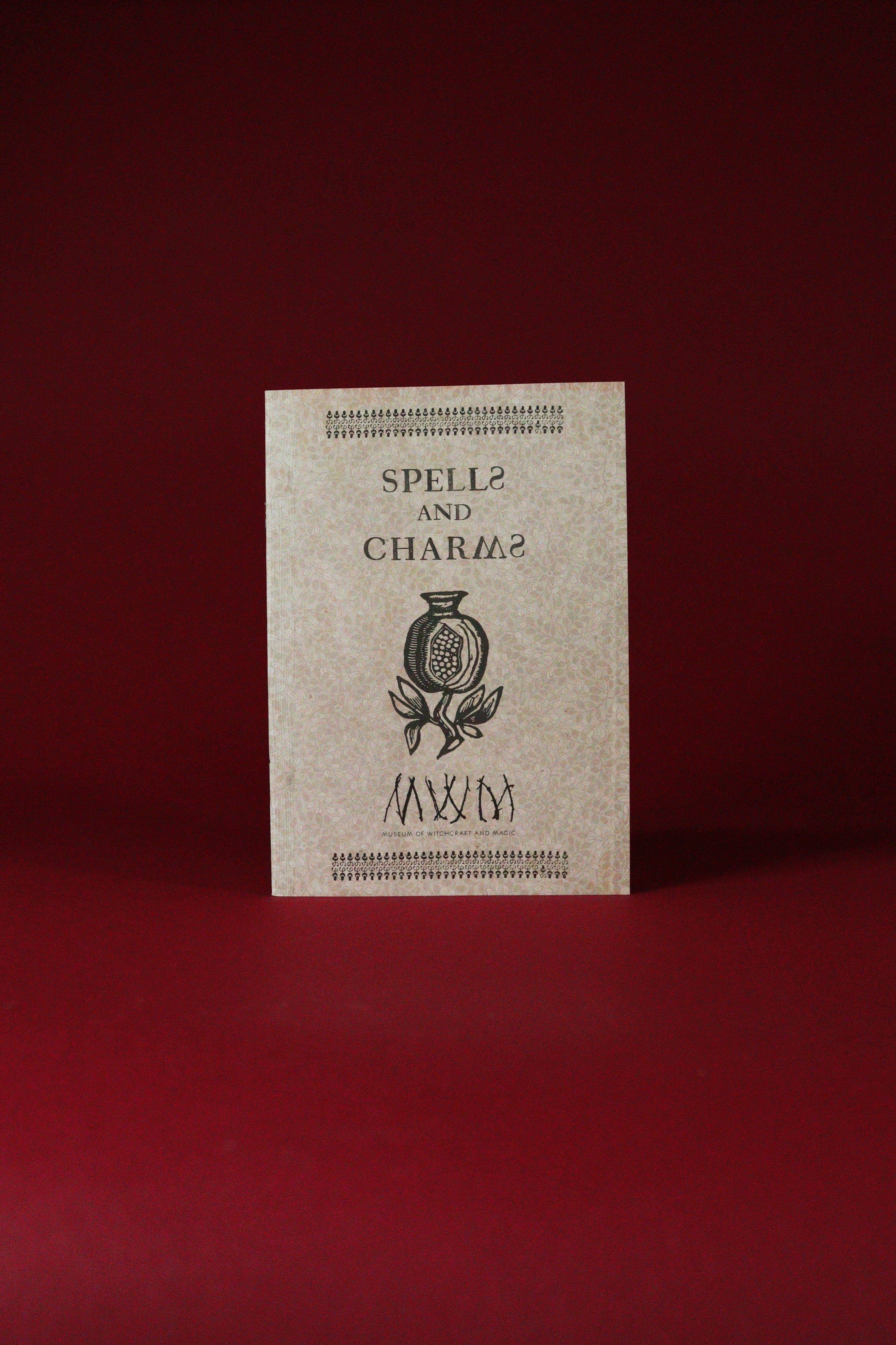 Booklet titled 'Spells and Charms' with a decorative cover on a red background