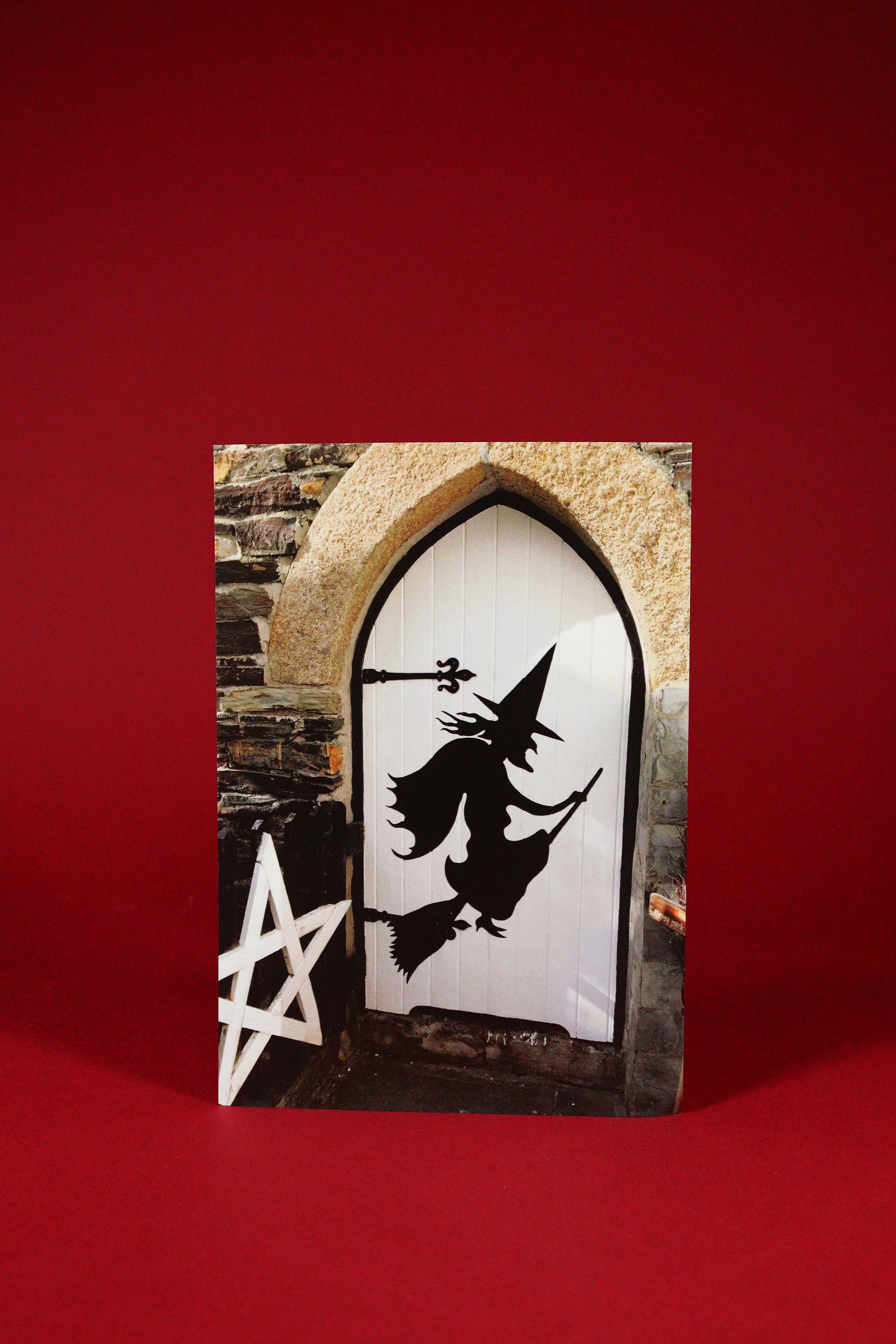 Decorative Door sign with a witch silhouette on a stone archway against a red background