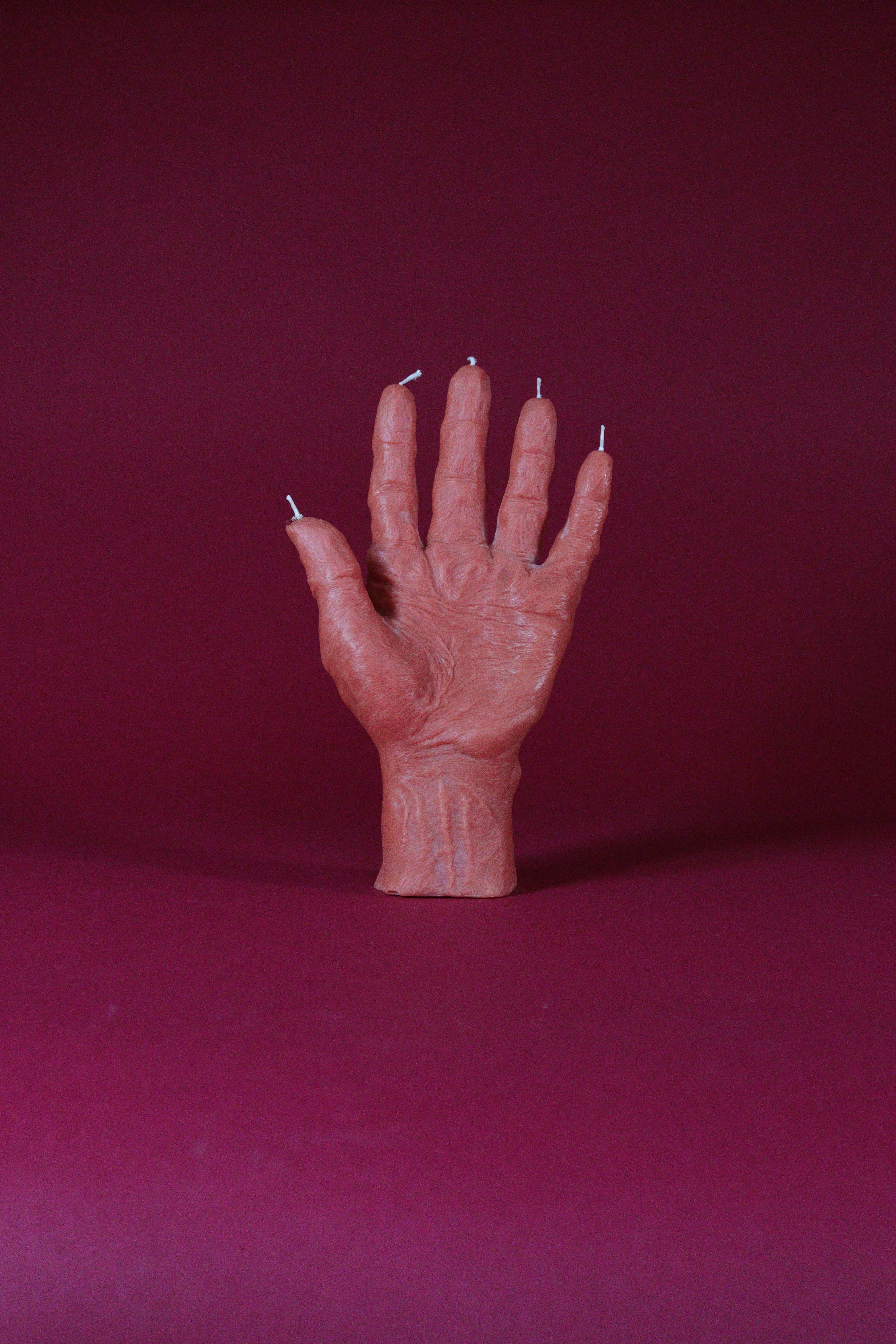 Hand-shaped candle on a red background