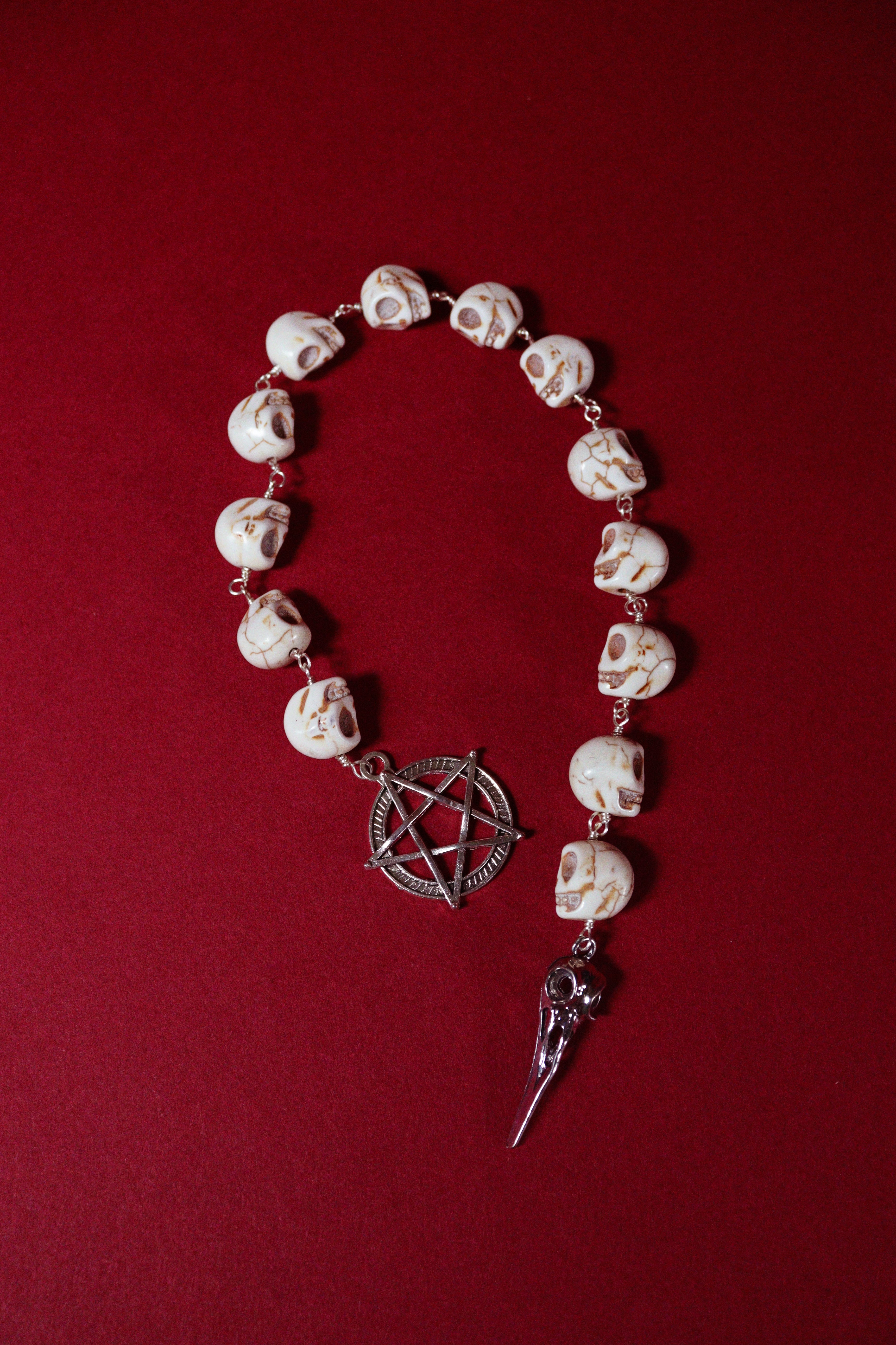 skull beads and pentagram charm on a red background